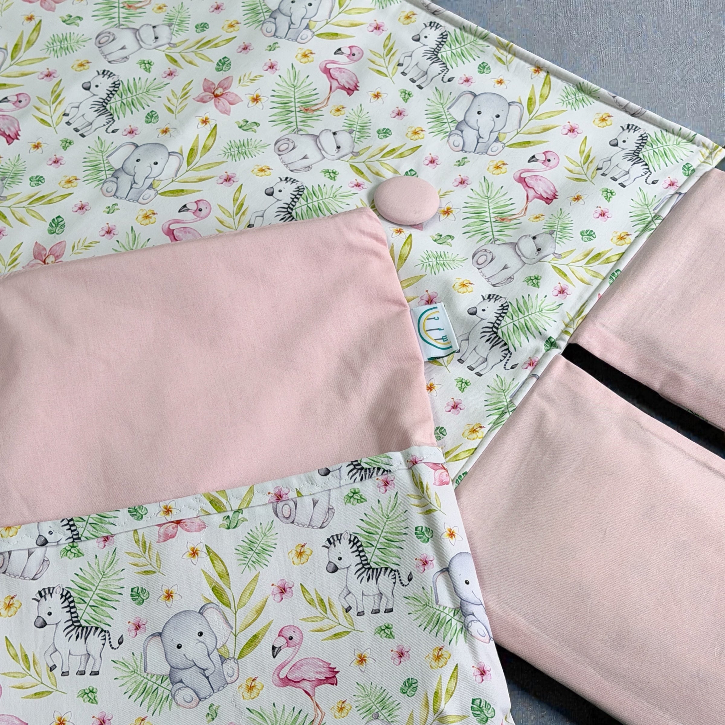 opened baby change mat with large pink button and jungle print in pink and green