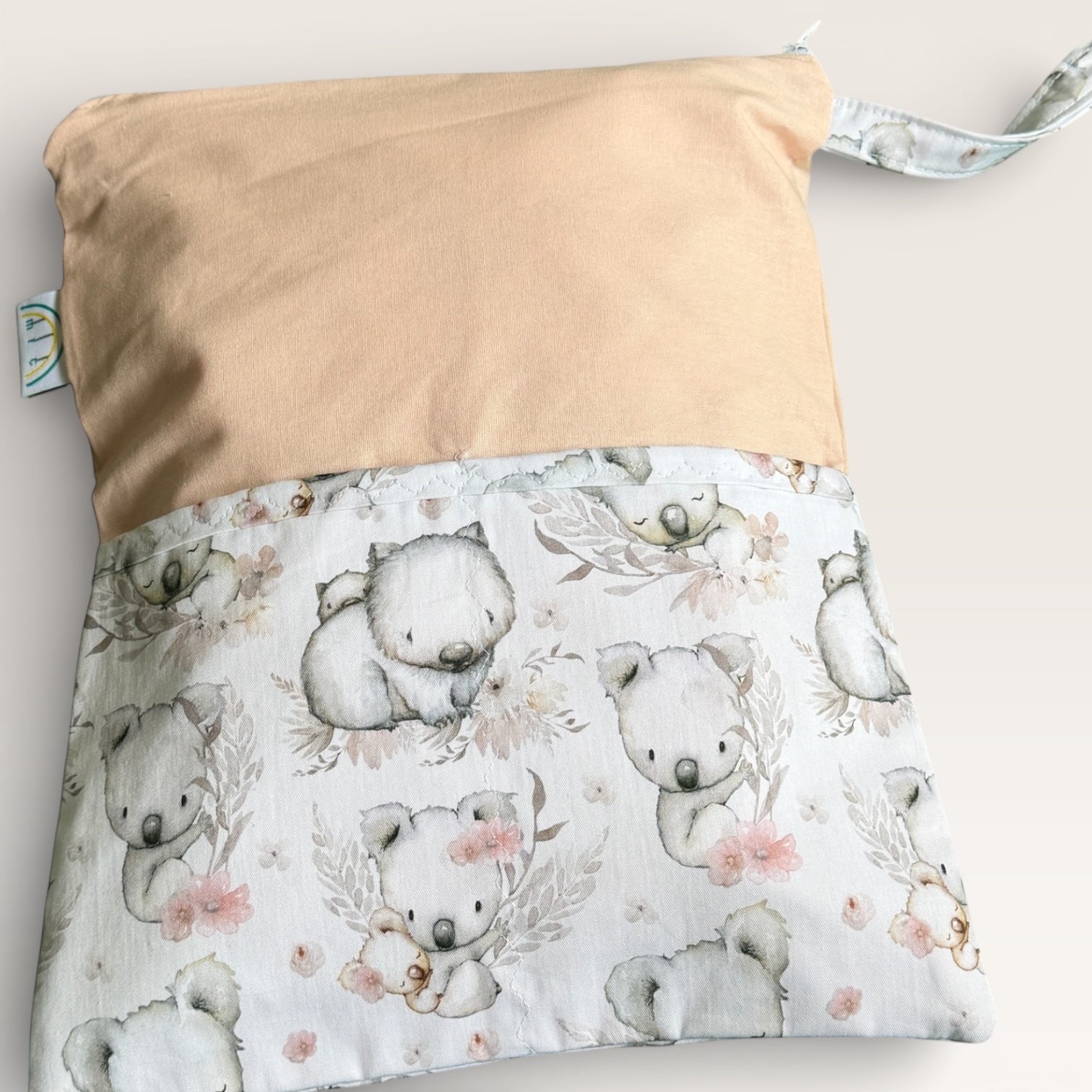 Baby change mat with koala pattern and peach coloured fabric on a light gray background