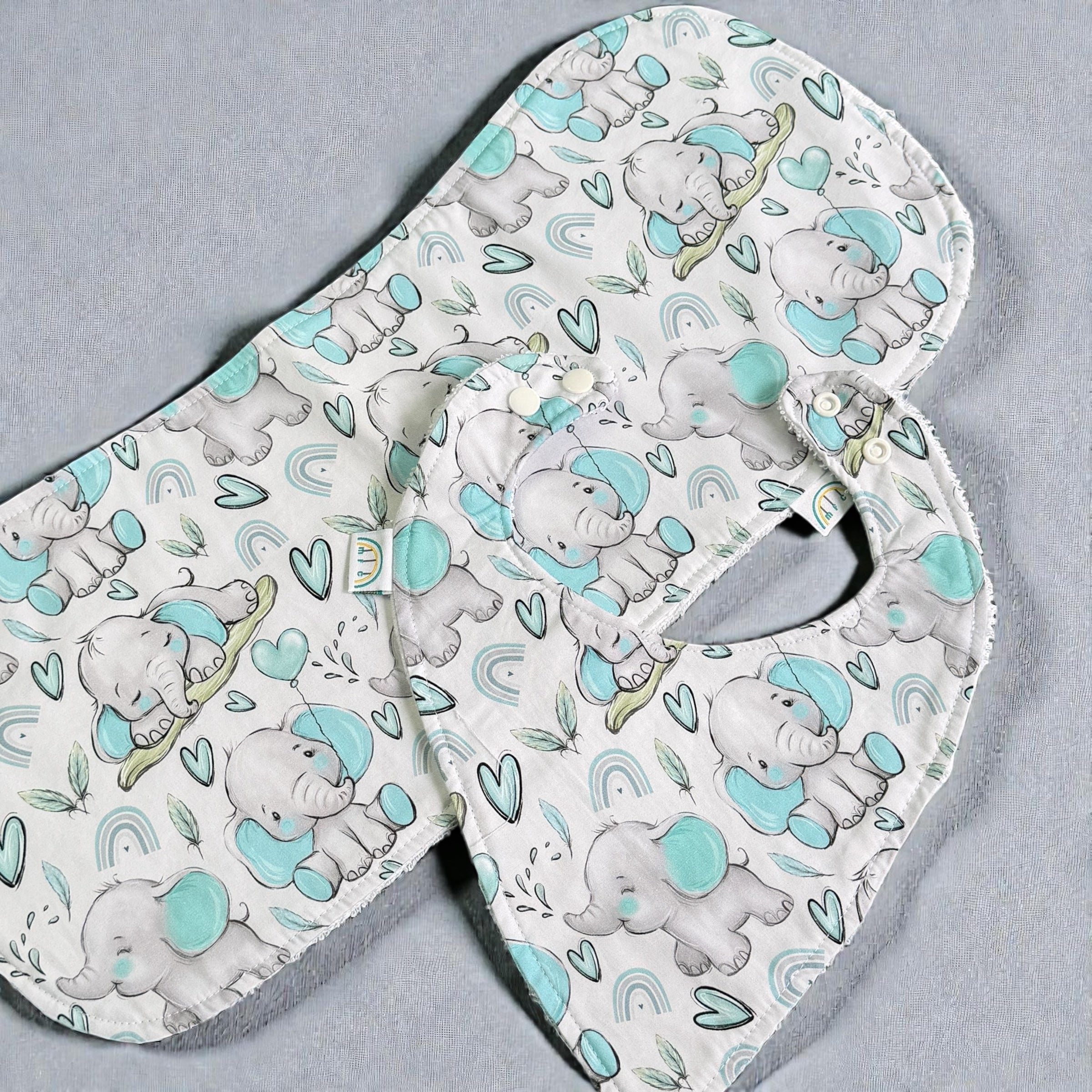 Baby bib and burp cloth with elephant pattern on a gray background