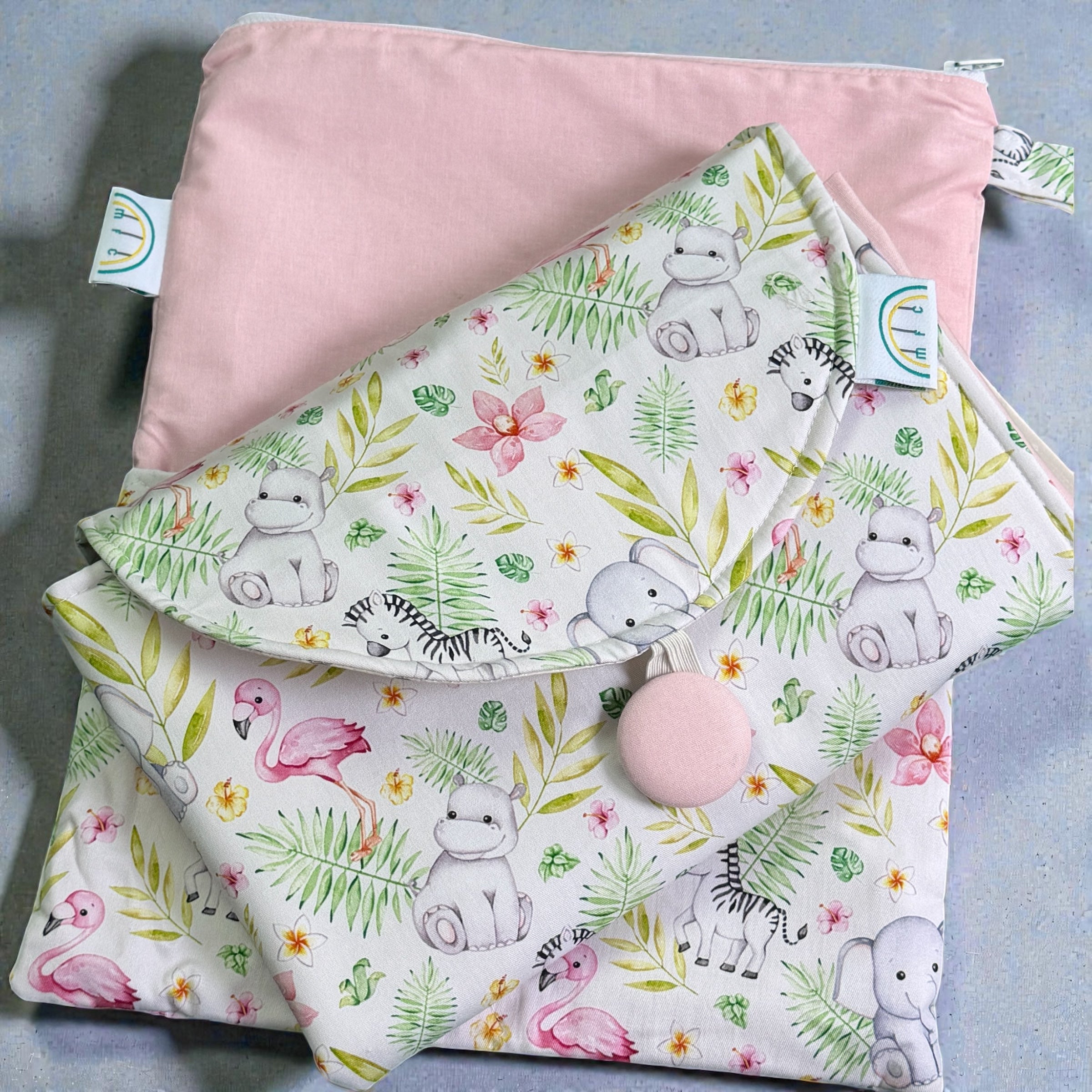 folded baby change mat with pink jungle animal and floral pattern on a white background