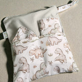 Baby change mat bib and burp cloth with dinosaur pattern on a beige surface