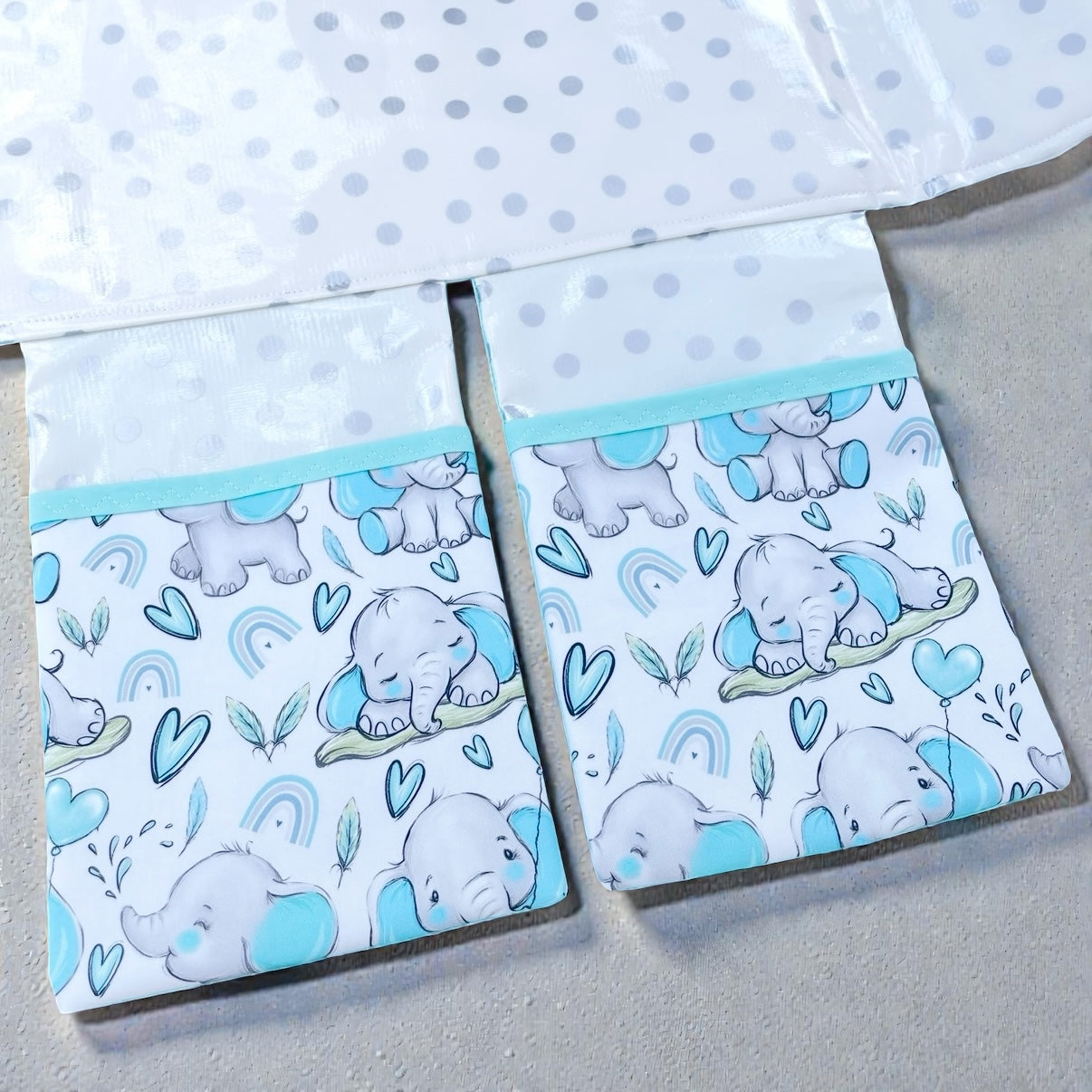 baby change mat showing 2 pockets attached to the mat wiht blue elephants on a gray background