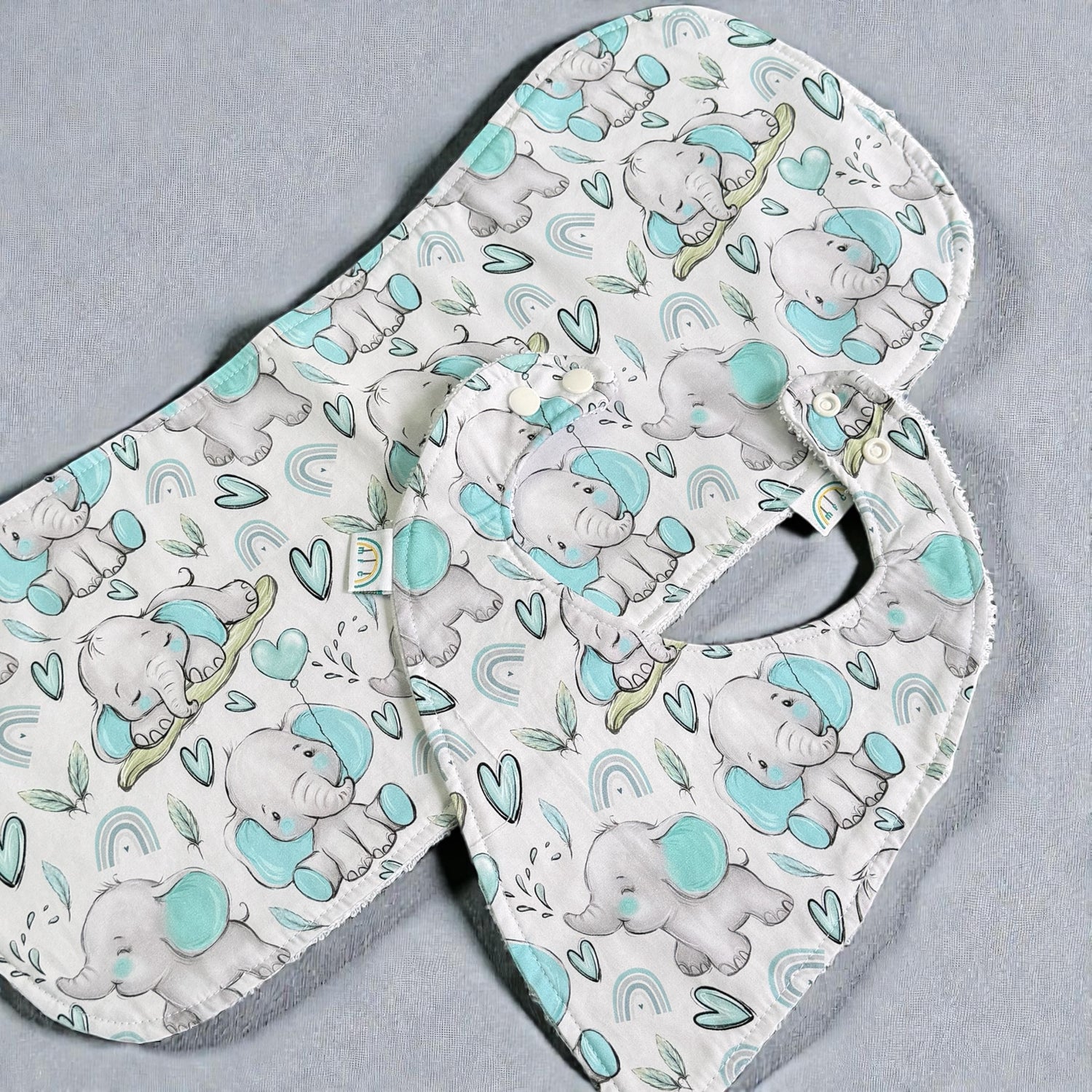 Baby bib and burp cloth with elephant pattern on a gray background