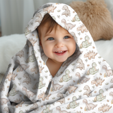 Toddler wrapped in a dinosaur-patterned soft swaddle