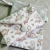 Folded change mat fabric with dinosaur pattern on a neutral background