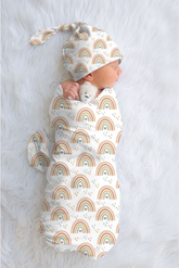 Newborn baby wrapped in a rainbow-patterned swaddle with matching hat on a light gray background
