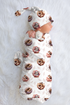 Baby wrapped in a floral baby animal patterned blanket on a white surface
